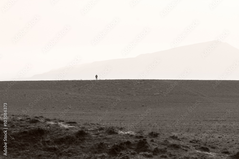 Distant man standing on plateau on hills in Azerbaijan. A sense of scale and smallness in hills not far from Baku, capital of Azerbaijan
