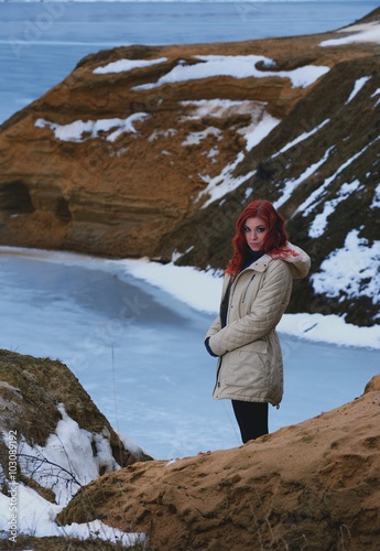 Beautiful redhead girl stays against Nordic landscape