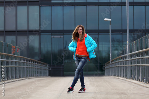 Beautiful blonde woman in jacket, blue jeans and sneakers on the street © ginkgofoto