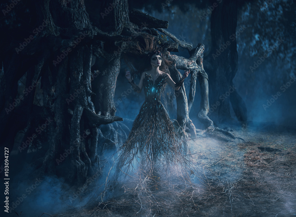 Obraz premium Duch wędruje po lesie w ciemnym magicznym lesie. Dziewczyna zapuściła korzenie w pobliżu potężnego dębu, mistyczny obraz, zaklęcia, moda kreatywne tonowanie kolorów
