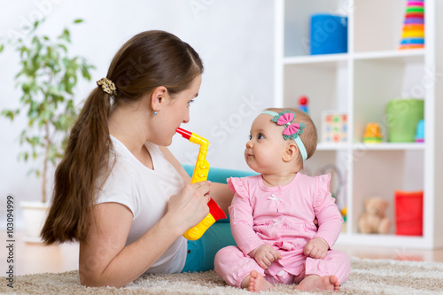 Happy family mom and baby daughter play musical toys