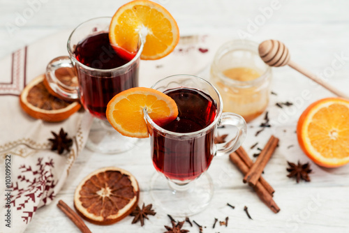  mulled wine with oranges , honey , cinnamon and cloves on a wooden background 