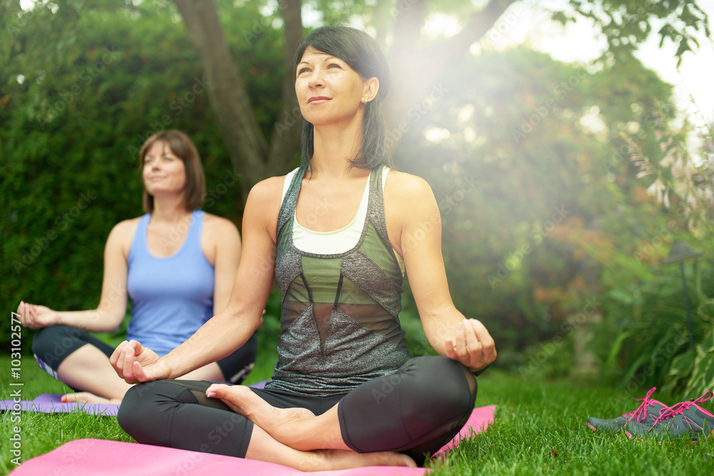Two mature women keeping fit by doing yoga in the summer Two mature women keeping fit by doing yoga in the summer