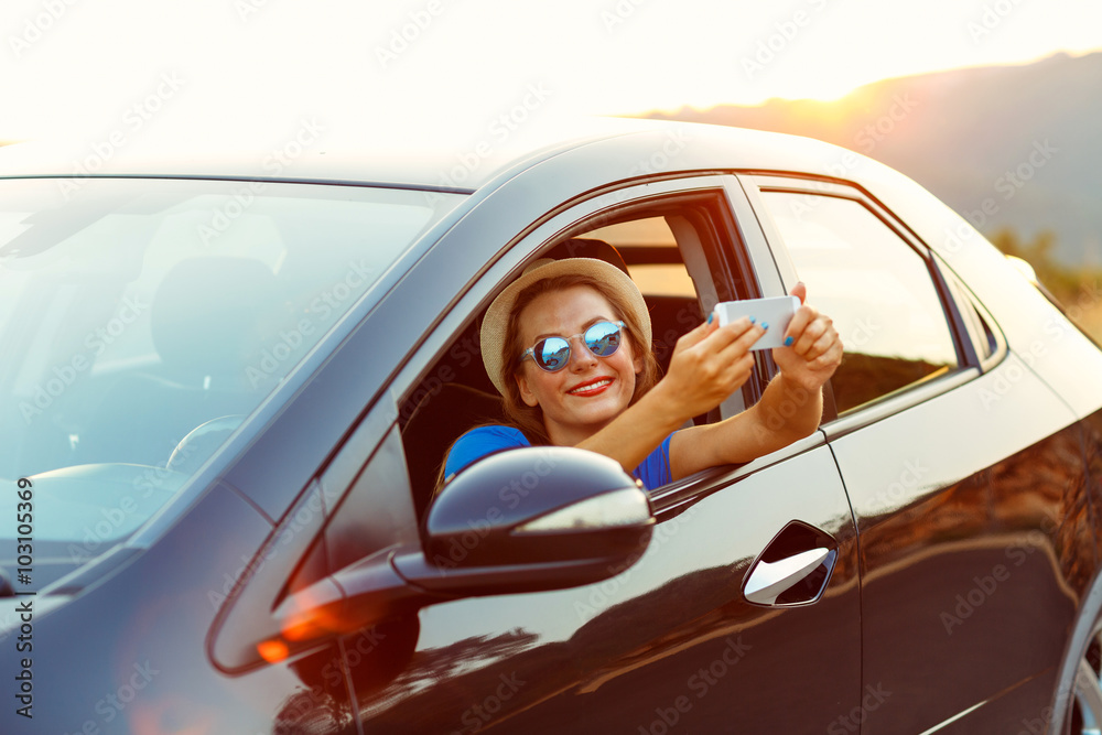 Naklejka premium Woman in hat and sunglasses making self portrait sitting in the