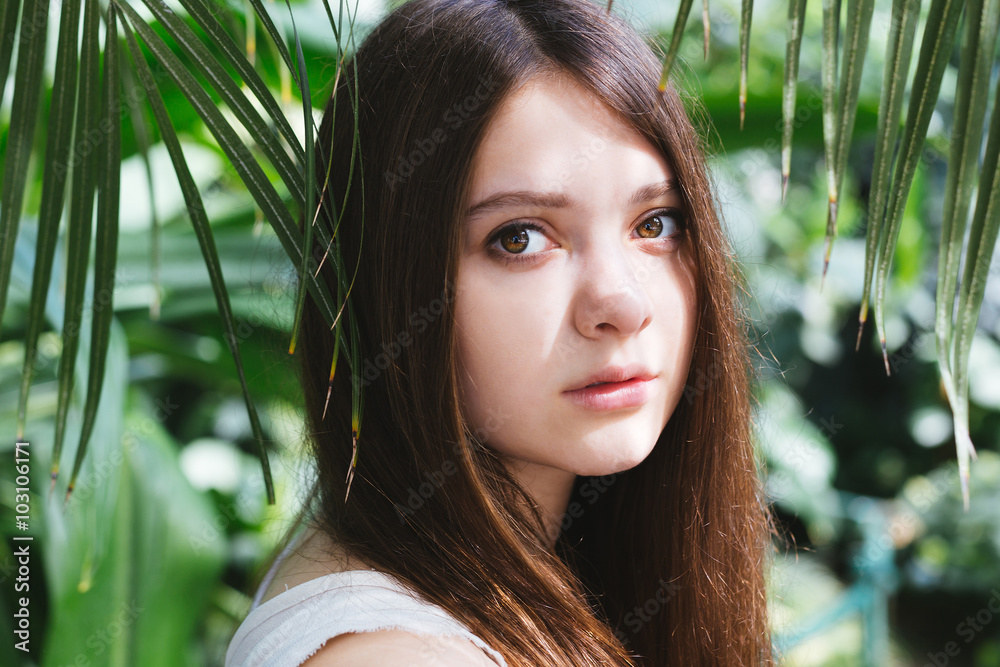 Young pretty girl posing near beautiful leaves and flowers Young pretty girl posing near beautiful leaves and flowers