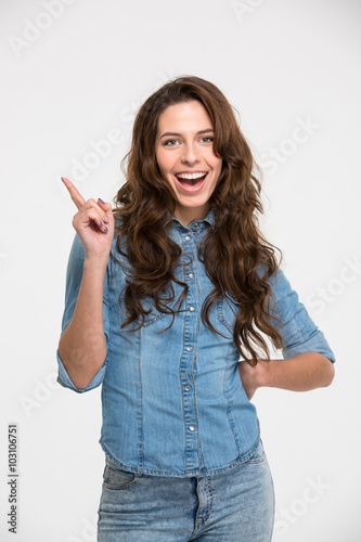 Cheerful pretty young woman standing and pointing away