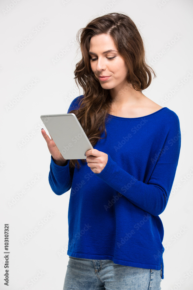 Smiling beautiful young woman standing and using tablet Smiling beautiful young woman standing and using tablet