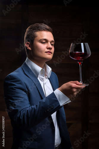 Young sommelier looking at red wine.