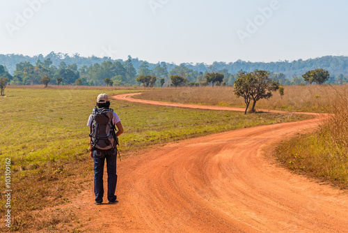 Woman Traveler with Backpack on dirt road.