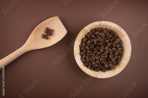 Coffee beans in bowl on brown background