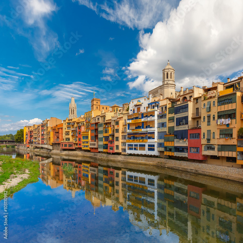 Colorful yellow and orange houses and famous house Casa Maso reflected in water river Onyar, in Girona, Catalonia, Spain. Church of Sant Feliu and Saint Mary Cathedral at background. © Kavalenkava