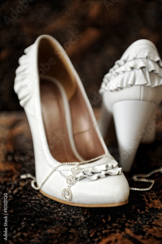 white bride's shoes and wedding accessories on the bed
