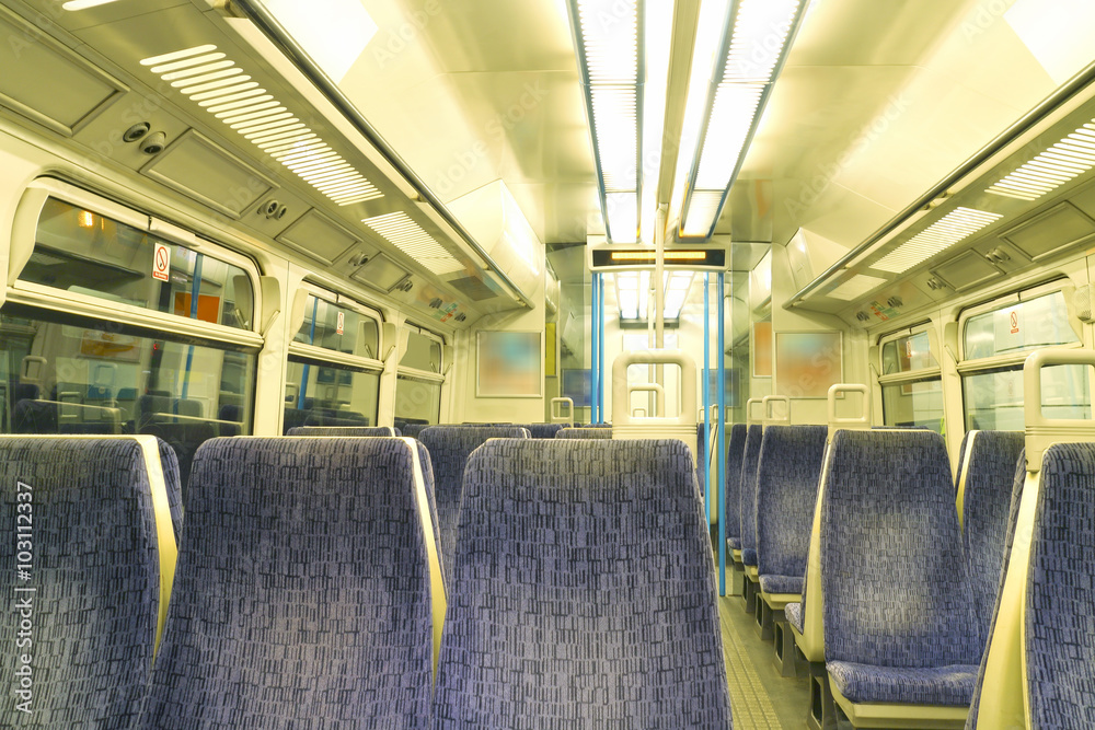 Empty passenger commuting train carriage interior with rows of blue seats