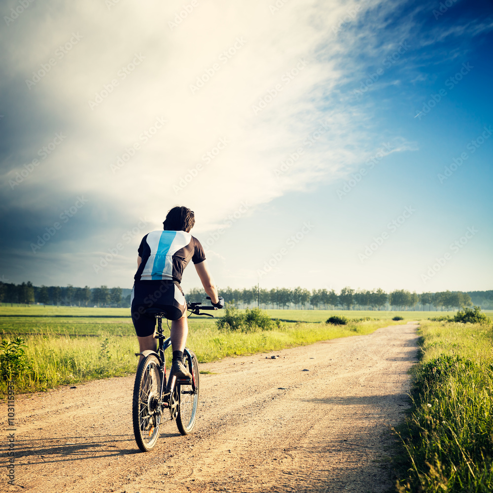 Fototapeta premium Cyclist Riding a Bike on the Country Road
