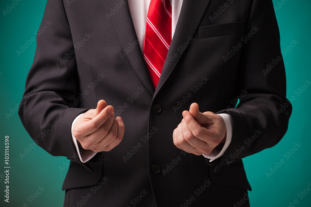 Businessman asking for money in black suit and red tie on green