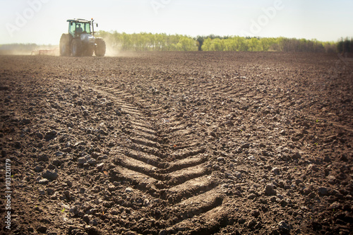 distant tractor closeup fresh track on wet spring ground photo