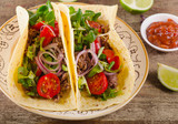 Two tacos on  rustic wooden table.