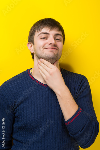 young man holding his hand on the necks yellow background
