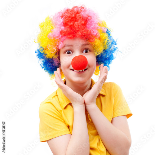 A surprised boy with a red clown nose and bright wig