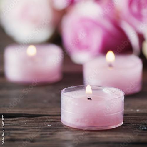 Pink roses and pinl candles on the wooden table