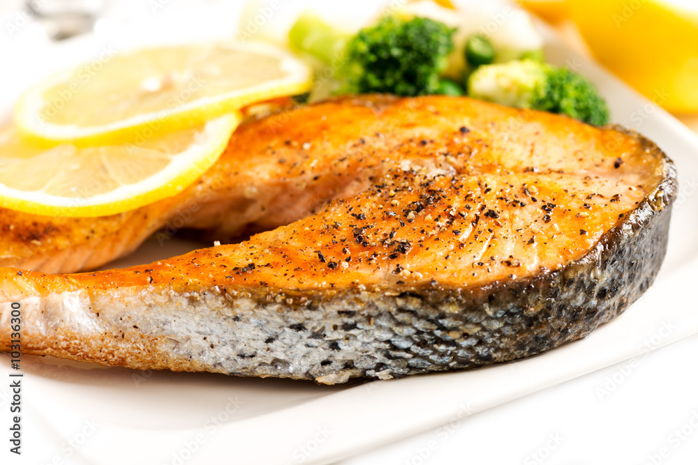 Grilled salmon and vegetables on white plate covered with pepper Grilled salmon and vegetables on white plate covered with pepper