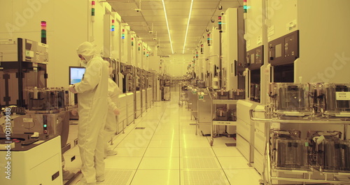 Workers in clean suits on the production floor of a semiconductor fabrication facility