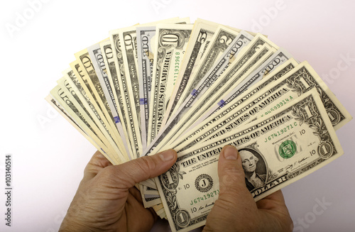Dollars of different denominations in hand.