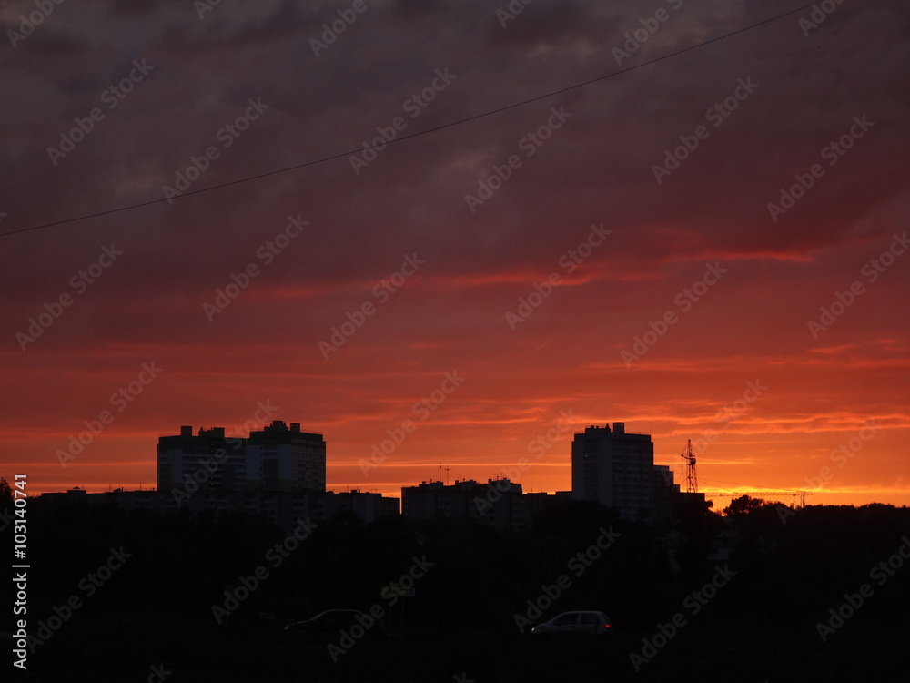 Красный закат над городом летним вечером