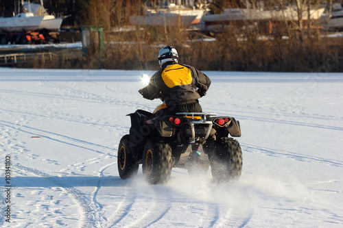 Quad bike driver rides over frozen lake