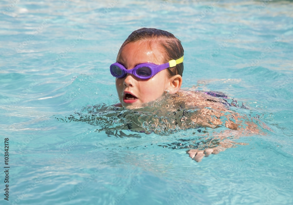 Young girl wearing goggles in swimming pool