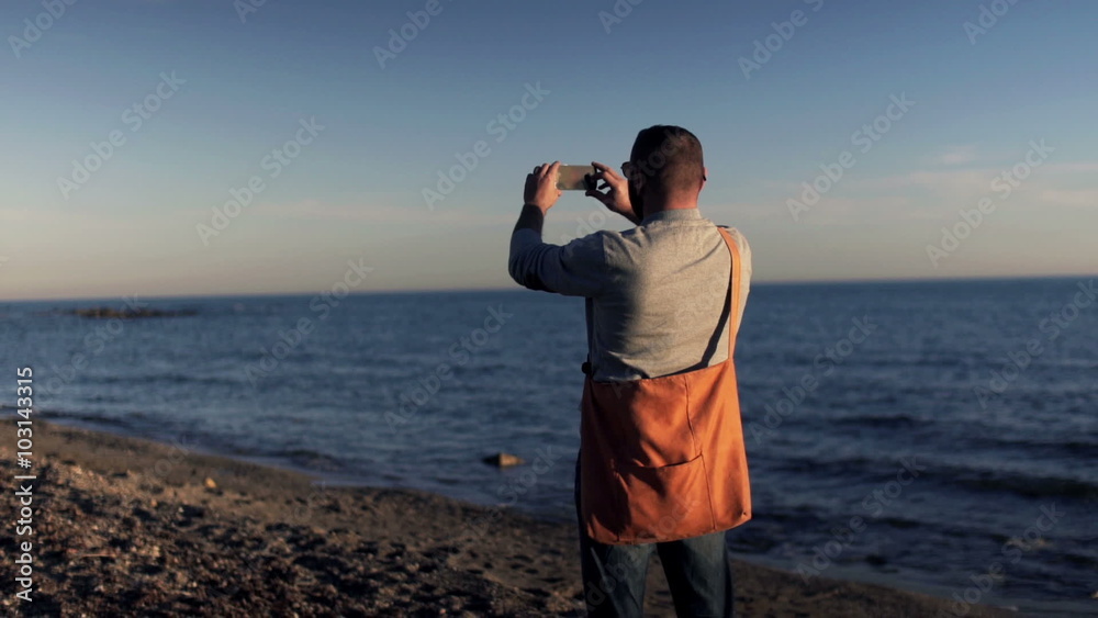 Young man taking picture of the sea with his cellphone o the beach
Young man taking picture of the sea with his cellphone o the beach