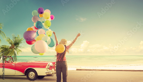 Happy young woman holding colorful balloons with floating, concept of journey honeymoon in summer on tripical beach blue sky - vintage color tone photo