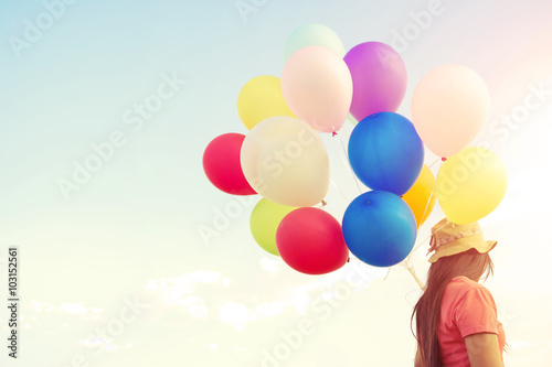 Woman hand holding multicolor balloons done with a vintage pastel filter effect - lifestyle concept in summer holiday