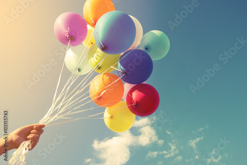 Girl hand holding multicolor balloons done with a retro instagram filter effect, concept of happy birth day in summer and wedding honeymoon party (Vintage color tone) photo