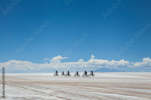 Gruppo di biciclette attraversa il Salares de Uyuni, Bolivia photo