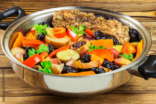 Healthy food, stewed pork meat with various colorful vegetables in pan on wooden background