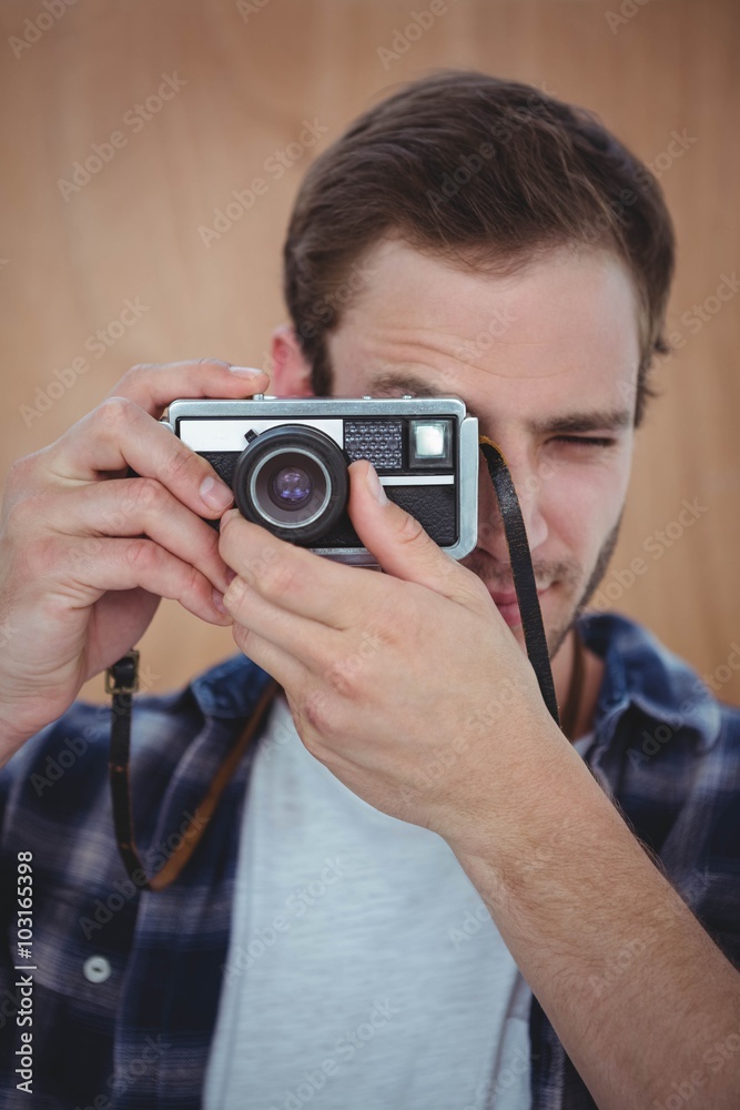 Handsome hipster taking picture with retro camera