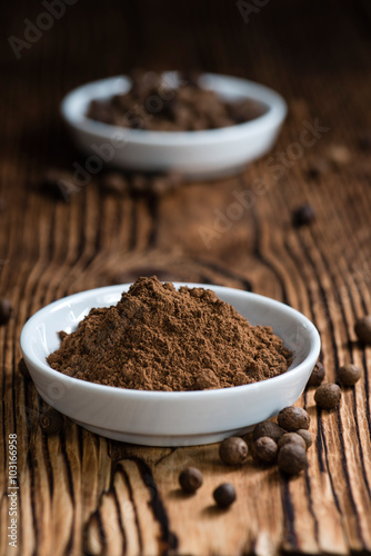 Old wooden table with Allspice powder