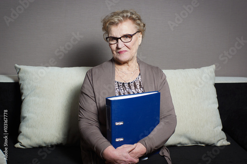 Old woman in glasses with a folder holding hands