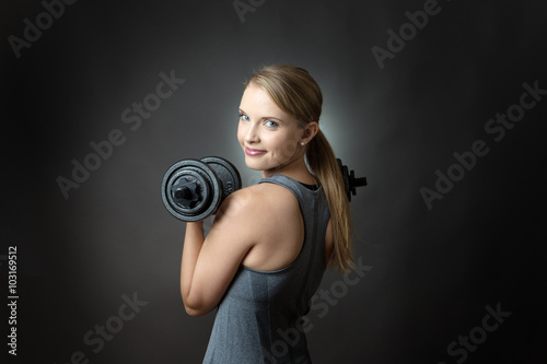 sporty woman on grey background with dumbbells © jayfish