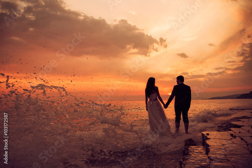 Fotografie A just married couple staying at the beach. Romantic wedding sun