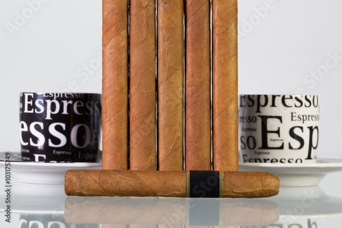 Different cigars and cups of coffee on a  glass table