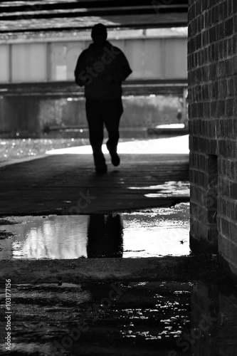 runner silhouette on towpath on canal river- Regents Canal, London