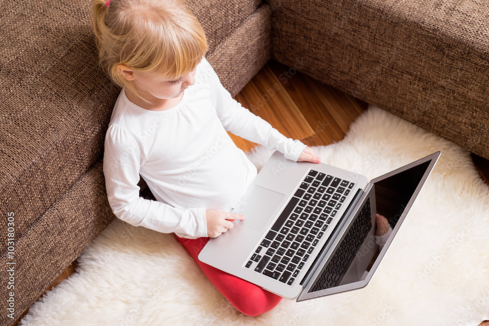 Little girl sitting on the ground with computer in her lap Little girl sitting on the ground with computer in her lap