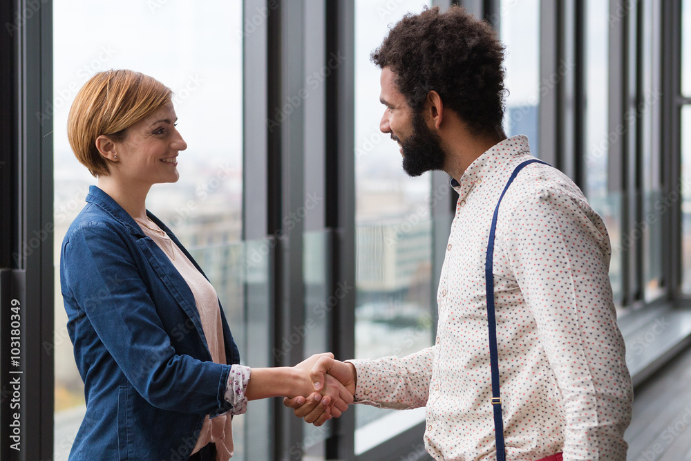 Young businessmen and business woman shaking hands in modern office hall. Young businessmen and business woman shaking hands in modern office hall.
