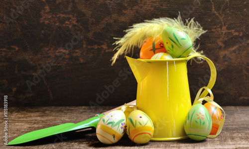œufs de Pâques décoratif dans arrosoir jaune sur fond bois