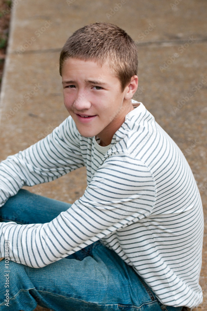 Cute teen boy sitting on sidewalk looking at camera Stock Photo | Adobe  Stock