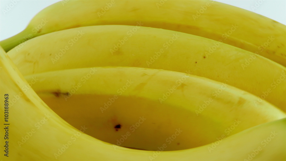 A macro shot of ripe yellow organic bananas rotating against a white background.
A macro shot of ripe yellow organic bananas rotating against a white background.