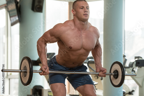 Bodybuilder Exercising Back With Barbell