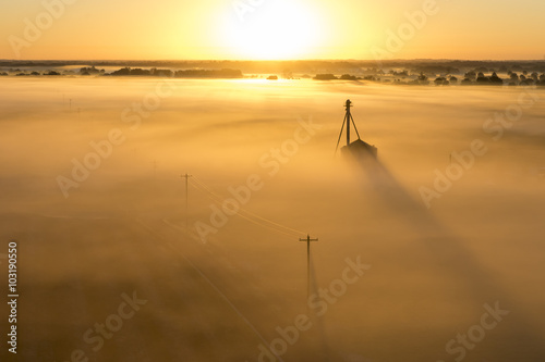 Telephone poles and farm ranch rural countryside silo on a foggy misty morning at sunrise or sunset